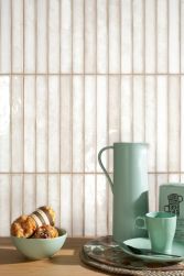 Ściana w kuchni wyłożona kremowymi płytkami w połysku Brick Raku Peral z drewnianym blatem z naczyniami