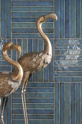 Ściana wyłożona niebieskimi płytkami w połysku Brick Raku Turquoise oraz dwie rzeźby flaming&oacute;w