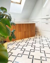 Łazienka z podłogą wyłożoną biało-czarną mozaiką Manorial Pure White Quadron, z wanną zabudowaną drewnem, białymi szafkami i dużym kwiatem