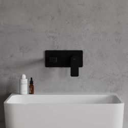 Widok od przodu na białą umywalkę z czarną baterią podtynkową Omnires Baretti na tle jasnoszarej ściany