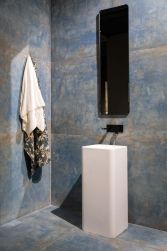 W łazience umywalka wolnostojąca, na ścianie podłużne prostokątne lustro, wieszaki z ręcznikami, podłoga i ściana wyłożone Flamed Saphhire Natural Rect. 59,55x59,55 płytki imitujące metal