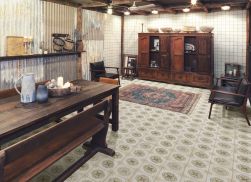 Pomieszczenie z podłogą wyłożoną dekoracyjnymi płytkami FS Porto Flavia z dywanem, drewnianym stołem z ławą, szafami i dwoma fotelami