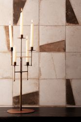 Ściana wyłożona postarzanymi płytkami patchworkowymi FS Sabi z ciemnym blatem i wysokim świecznikiem