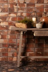 Ściana wyłożona brązowymi cegiełkami rustykalnymi FS Iron Oxide z drewnianym stołem z ozdobami