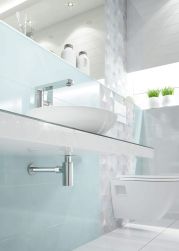 Łazienka z błękitną ścianą, białym blatem, umywalką nablatową i syfonem ozdobnym w chromie Deante