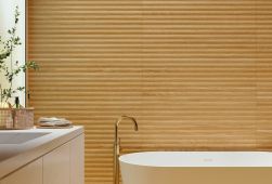 Ściana w łazience wyłożona płytkami drewnopodobnymi ze żłobieniami Granier Honey Decor, z białą wanną i szafką z umywalką