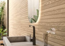 Widok na ścianę w łazience wyłożoną płytkami drewnopodobnymi ze żłobieniami Grow Kalua SP z okrągłym lustrem i szarą, betonową umywalką