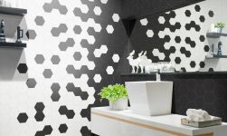 Umywalka nablatowa w białym kolorze, jasna półka pod umywalką, wbudowane prostokątne lustro, na blacie dekoracje, część ściany wyłożona czarnymi heksagonami oraz Hexa Hub Blanco 14x16 płytka heksagonalna