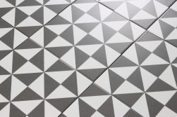Zbliżenie na powierzchnię biało-czarnych płytek patchworkowych geometrycznych Terrades Grafito 20x20