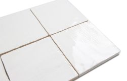 Zbliżenie na białe cegiełki ścienne w połysku z delikatnym wzorem Aquarelle Blanc 10x10