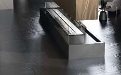 Pomieszczenie z podłogą wyłożoną szarymi płytkami dekoracyjnymi Luce Silver i z kominkiem na środku
