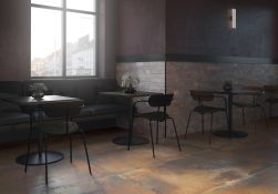 Restauracja w stylu industrialnym z brązowymi płytkami imitującymi metal Iron Oxide na podłodze z szarą kanapą, ciemnymi, kwadratowymi stolikami i krzesłami