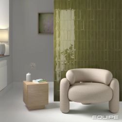 Pokój z zielonymi cegiełkami Island Lichen na ścianie z fotelem i stolikiem