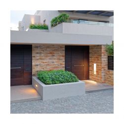 Elewacja domu z szerokimi. brązowymi drzwiami, krzakami i kamieniem dekoracyjnym Costa Sand