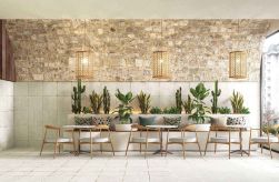 Wnętrze restauracji, stoliki, krzesła, dekoracyjne lampy, oraz rośliny, część ściany i podłoga wyłożone Kintsugi White Aichi Natural 30,5x30,5 płytki dekoracyjne