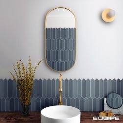 Widok na ścianę w łazience wyłożoną do połowy niebieskimi cegiełkami z kolekcji Lanse z drewnianym blatem z białą umywalką nablatową i baterią stojącą, kwiatami w wazonie, podłużnym lustrem i kinkietem