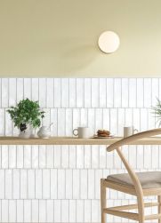 Ściana do połowy wyłożona białymi cegiełkami Legacy Snow z drewnianym blatem, krzesłem, dwoma kubkami, talerzem z naleśnikami, dzbankiem i kwiatem