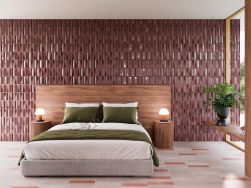 Sypialnia ze ścianą za łóżkiem wyłożoną bordowymi płytkami trójwymiarowymi z drewnianym zagłówkiem, dwoma okrągłymi stolikami i półką pod oknem z kwiatem