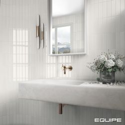 Fragment łazienki ze ścianą wyłożoną białymi cegiełkami z kolekcji Limit z białą półką wiszącą z umywalką, baterią podtynkową, wazonem z kwiatami, lustrem i kinkietem