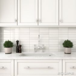 Klasyczna kuchnia z białymi meblami i przestrzenią pomiędzy nimi wyłożoną białymi cegiełkami z kolekcji Limit z baterią kuchenną stojącą w chromie i dwoma kwiatami