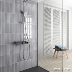 Kabina prysznicowa z ciemną podłogą i ścianą wyłożoną szarymi cegiełkami z kolekcji Limit z zestawem prysznicowym oraz małym taboretem z ręcznikami