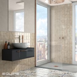 Jasna łazienka z kabiną prysznicową, oknem z widokiem na miasto, wiszącą szafką czarną z umywalką nablatową, lustrem i beżowymi cegiełkami z kolekcji Manacor
