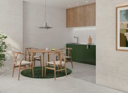 Minimalistyczna kuchnia wyłożona jasnoszarymi płytkami betonowymi lastryko Manhattan Silver z zielonymi meblami i dywanem, okrągłym stołem z krzesłami, lampą wiszącą i obrazem na ścianie