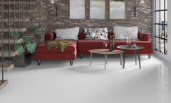 industrialny salon, czerwona kanapa, ceglana ściana, ciekawe schody, duże okno, na podłodze płytki method blanco semipolished