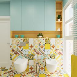 Kolorowa łazienka z żółtymi płytkami patchwork, z białą miską WC wiszącą Decos Slim i białym bidetem i błękitnymi szafkami