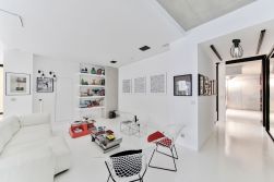 Biały salon z białą kanapą, dwoma białymi fotelami i czarną lampą sufitową