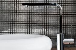 Ściana w łazience wyłożona srebrną mozaiką Dinox z umywalką i baterią