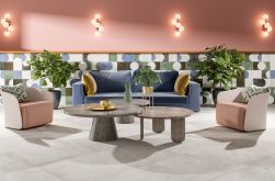 Salon, niebieska kanapa, dwa beżowe fotele, na środku dwa okrągłe stoliki kawowe, ściana w części wyłożona dekoracyjnymi kolorowymi płytkami, na podłodze płytki Mud White Natural 59,2X59,2 płytka imitująca beton