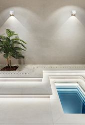 Podłoga wyłożona białymi płytkami imitującymi kamień Nature White z małym basenem, drzewkiem i dwoma kinkietami na ścianie