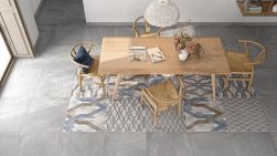 Pokój z jasnym, drewnianym stołem, czterema krzesłami, białą lampą wiszącą i płytkami podłogowymi imitującymi beton Salem Gris 60,8x60,8