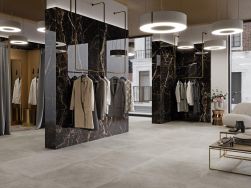 Elegancki sklep odzieżowy ze ściankami na środku wyłożonymi brązowymi płytkami imitującymi marmur Lux Laurants Brown z wieszakami z ubraniami