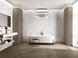 Elegancka łazienka ze ścianami wyłożonymi płytkami imitującymi marmur Torano Dorado z białą wanną wolnostojącą, wiszącymi umywalkami, lustrem i lampą wiszącą