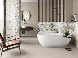 Łazienka z dekoracyjnymi elementami w postaci jasnych płytek imitujących marmur Lux Grotta Oro, z białą wanną wolnostojącą, fotelem, prysznicem za przepierzeniem, półką wiszącą z umywalką oraz okrągłym lustrem