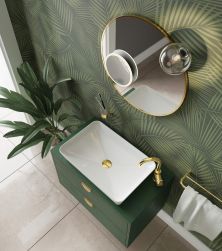 Łazienka z zieloną ścianą z motywem liści, zieloną szafką z białą umywalką nablatową Deante Tess ze złotym korkiem i złotą baterią, okrągłym lustrem, kinkietem, ręcznikiem na złotym wieszaku i kwiatem w donicy