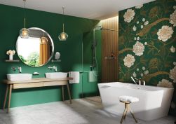 zielona łazienka, kwiatowa tapeta za wolnostojącą wanną, okrągłe lustro, dwie umywalki, stolik obok wanny na ręczniki, nawannowa bateria 3-otworowa, duża kabina prysznicowa