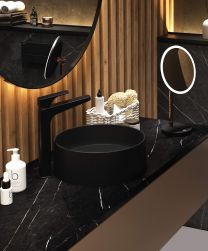 Ciemna łazienka z czarnym, marmurowym blatem na szafce wiszącej z czarną umywalką nablatową okrągłą Deante Silia z czarną baterią stojącą i z dwoma okrągłymi lustrami
