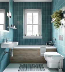 Łazienka wyłożona niebieskimi płytkami z zabudowaną wanną, wiszącą miską WC i białą umywalką ścienną Jasmin