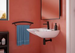 Łazienka z czerwonymi ścianami, białą umywalką ścienną i czarnym syfonem ozdobnym Deante