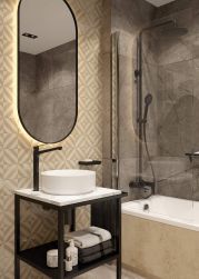 Na blacie umywalka w białym kolorze, łazienka urządzona w beżowym kolorze, na ścianie lustro, przy umywalce Deante Jasmin Bateria umywalkowa wysoka czarna BGJ_N20K