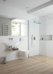 Jasna łazienka z białymi ścianami, wiszącą umywalką z baterią umywalkową podtynkową w chromie Deante Alpinia, dużym lustrem i ściankąprysznicową