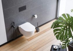 szare płytki na ścianie, drewniana podłoga, biała toaleta, roślina w rogu, czarna szczotka do WC Mokko
