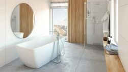 Łazienka z białą wanną wolnostojącą oraz baterią Anemon Bis, z kabiną prysznicową, dużym okrągłym lustrem, drewnianym blatem i oknem