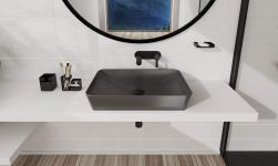 białą łazienka z czarną armaturą i czarnymi bateriami, okrągłe lustro nad umywalką, obok podwójny kubek Mokko