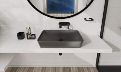 Jasna łazienka z białą półką i szarą umywalką nablatową z czarnym korkiem klik-klak z czarną baterią podtynkową, okrągłym lustrem i kabiną prysznicową