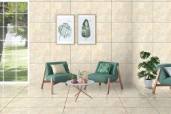 Pomieszczenie wyłożone beżowymi płytkami imitującymi kamień w połysku Rhodos Crema Polished z dwoma zielonymi fotelami, białym okrągłym stolikiem, kwiatem w donicy i dwoma obrazami