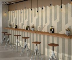 Restauracja ze ścianą wyłożoną pastelowymi płytkami z kolekcji Rhombus, drewnianymi blatami, taboretami i wiszącymi lampami
